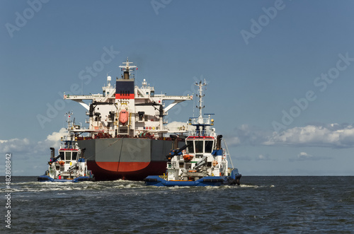 BULK CARRIER - The ship sails from port to sea secured by tugs