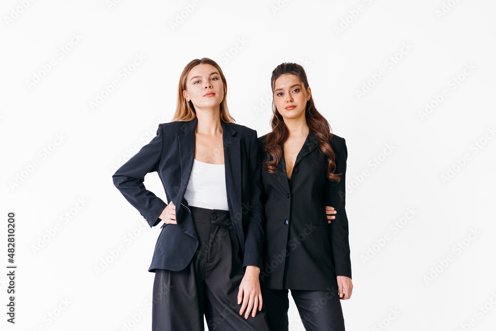 Concept of partnership in business. Two Young businesswoman dressed black formal suit standing studio isolated white background.