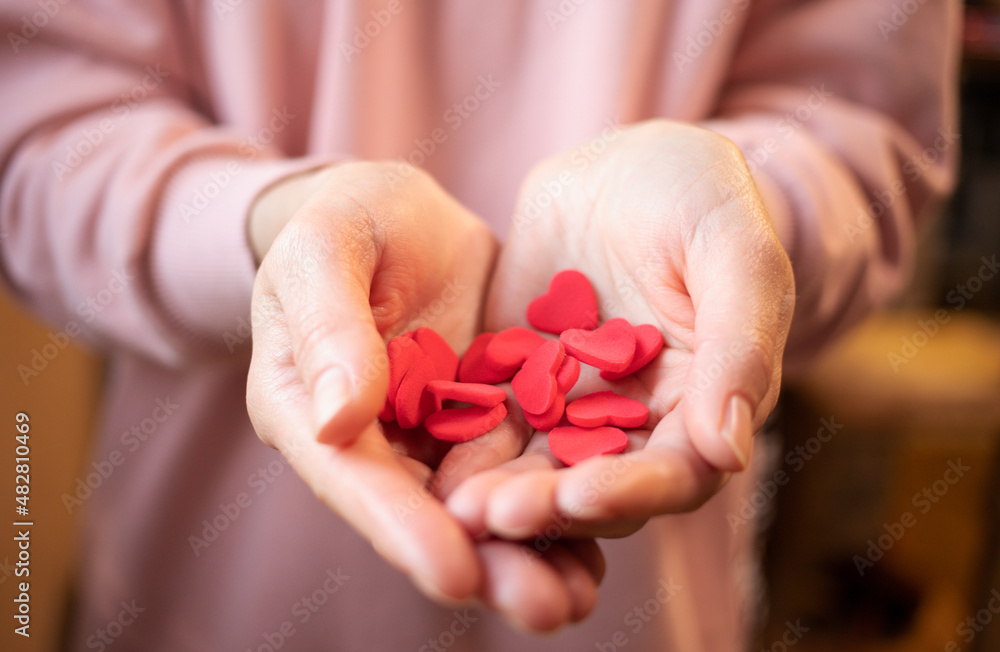 Hands holding red valentines on valentine's day. The girl's hands hold a lot of small hearts and fast-setting plasticine. The 14th of February. Holiday of love. The concept of giving love. give life Hands holding red valentines on valentine's day. The girl's hands hold a lot of small hearts and fast-setting plasticine. The 14th of February. Holiday of love. The concept of giving love. give life