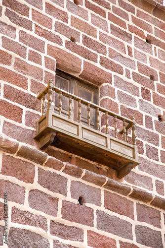fenêtre avec vieux balcon en bois mur en pierre rouge