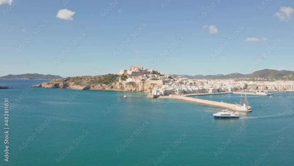 Ibiza, Spain - Boat leaving port of Ibiza City Eivissa. Filmed by drone aerial. Ibiza City in background, ocean in foreground Ibiza, Spain - Boat leaving port of Ibiza City Eivissa. Filmed by drone aerial. Ibiza City in background, ocean in foreground