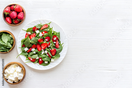 Fototapeta Naklejka Na Ścianę i Meble -  Vegetarian lunch spinach and strawberry salad. Top view
