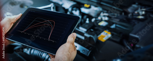 car engine ecu remapping and diagnostics. mechanic using digital tablet to check vehicle performance after chiptuning photo
