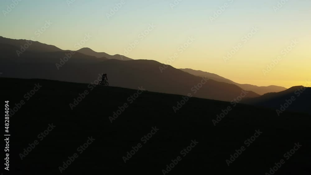 Aerial video shot of a cyclist riding in the mountains at sunset. Drone 4k footage