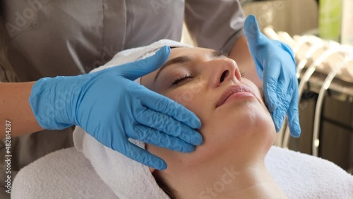 A young beautiful girl lies on the table at the beautician and receives procedures, a light massage, hands in blue gloves, the skin is smooth	  