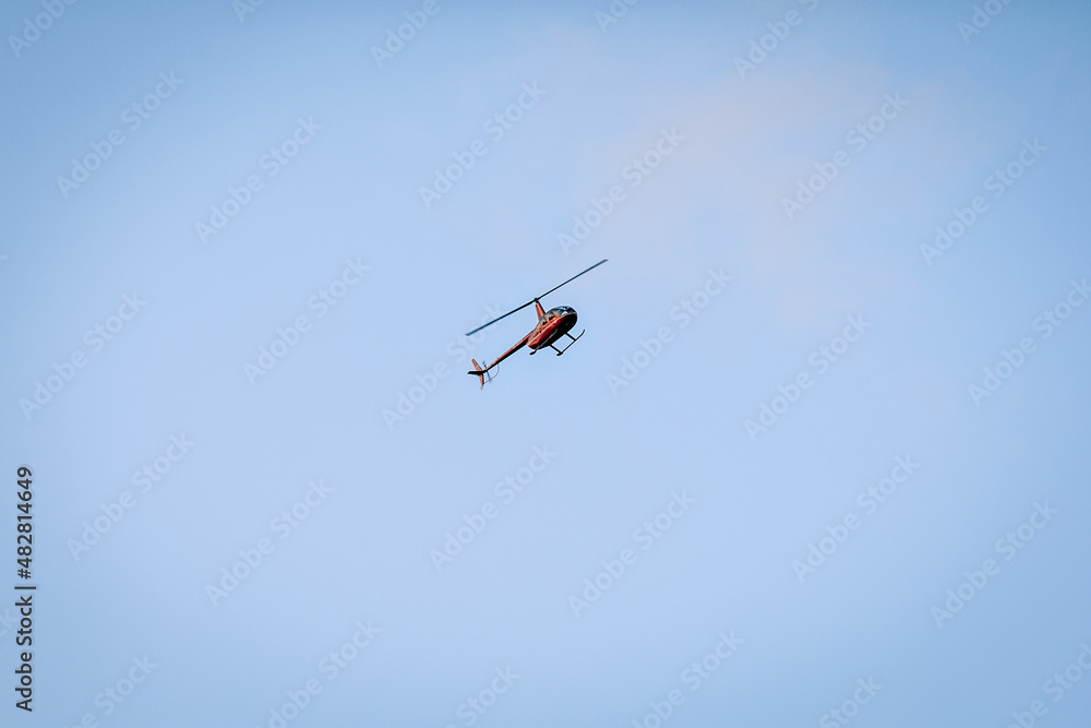 Silhouette of a chopper high in the blue sky seen from below, the military maneuvers; worm’s eye view. Silhouette of a chopper high in the blue sky seen from below, the military maneuvers; worm’s eye view.