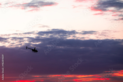 The helicopter in the astonishingly beautiful evening sky at sundown, rescue mission; aerial vehicle concept.