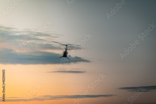 Helicopter against the morning sky, some scattered clouds, emergency mission in progress; aerial vehicle concept.