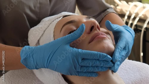 A young beautiful girl lies on the table at the beautician and receives procedures, a light massage, hands in blue gloves, the skin is smooth	  
