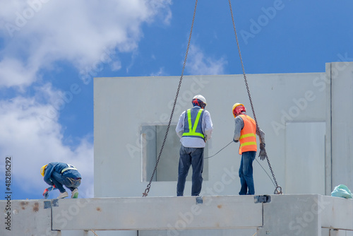 Construction worker are installing the precast concrete beam at housing estate, build a house, Worker wearing Safety Uniform, safety helmet and color vest.
