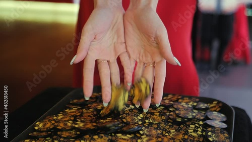 A girl in a red dress with a beautiful manicure picks up poker chips