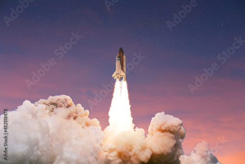 Successful launch of a rocket into space at sunset. Spaceship takes off up into the pink blue sky. Launch startup business  concept
