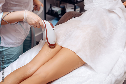 Laser hair removal on women's legs. The cosmetologist conducts a laser hair removal procedure for his client. Renewing your body. Cosmetic procedure. Nice legs. The concept of care procedures.
