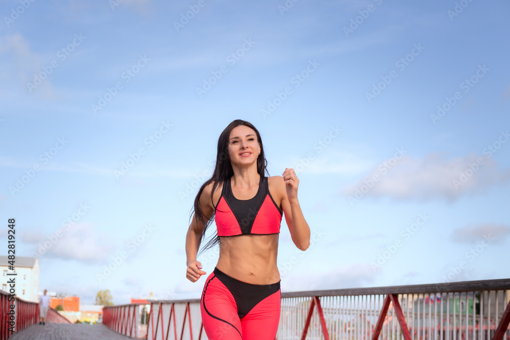 A woman in a pink sweat suit runs across the bridge