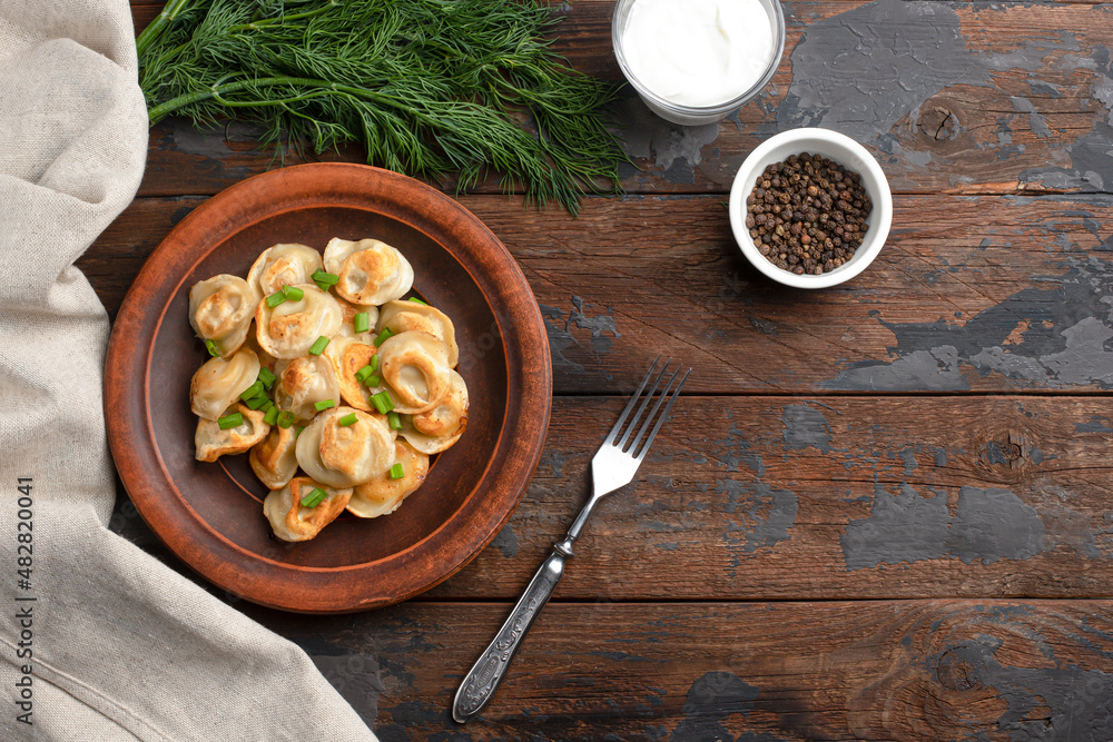 fried dumplings with pepper, sour cream, with appliances on a wooden background top view, Russian national food