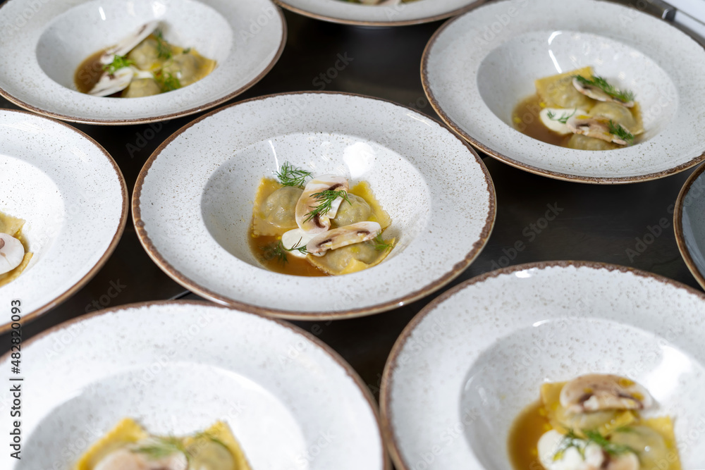 Dumplings, dumplings, with egg and decorated with champignons, dill. Plates stand in the restaurant. Dumplings, dumplings, with egg and decorated with champignons, dill. Plates stand in the restaurant.