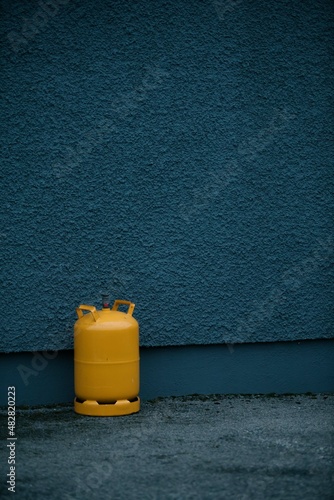 Botella de butano naranja sobre pared azul photo