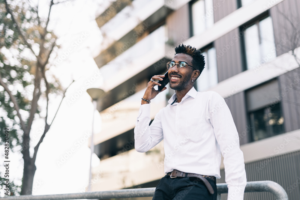 Young elegant black businessman in white shirt talking on his smartphone Young elegant black businessman in white shirt talking on his smartphone
