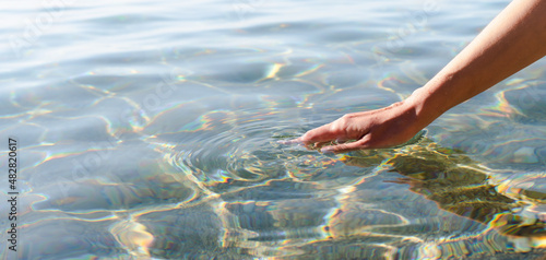 A woman's hand touching the sea water. Banner. Copy space. Selective focus.