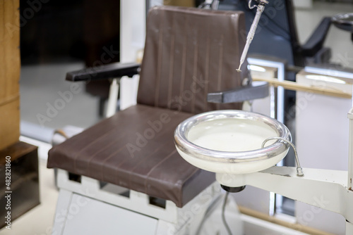 An old Soviet dental sink against a brown armchair. Dentistry of the times of the USSR. Soft focus © jockermax3d