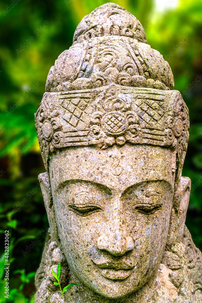 Traditional asian sculpture of Buddha on green natural background, Ubud, Bali, Indonesia