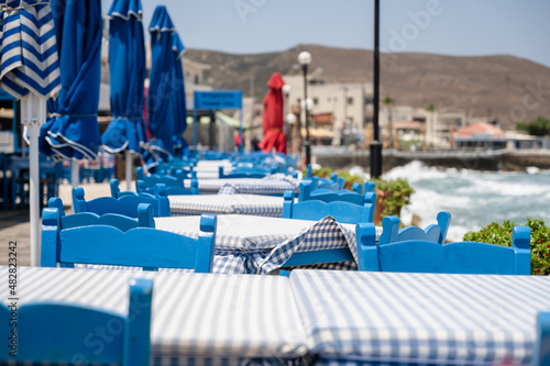 Seaside blue chairs and table, typical Greek tavern in Kissamos, Crete, Greece.