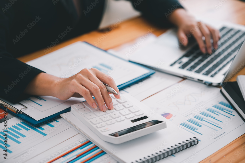 business woman or accountant who are using a calculator to calculate business data Accounting documents and laptop computer at the office business idea business woman or accountant who are using a calculator to calculate business data Accounting documents and laptop computer at the office business idea