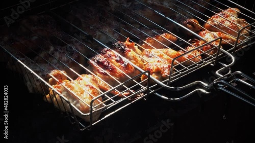 Close-up shot of cooking chicken on cover charcoal. Baking and roasting marinated legs and wings on barbecue grill.
