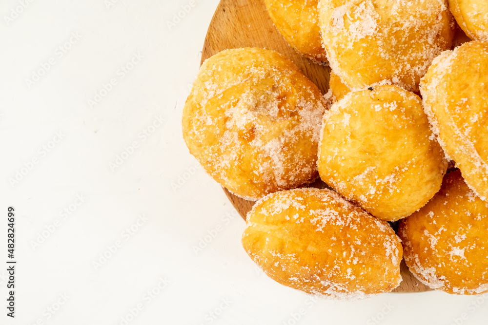 Lots of portuguese malasadas donuts sprinkled with sugar on a white table top view. Close-up. free space.