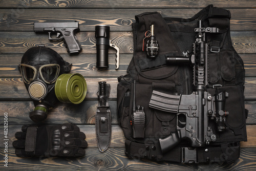 Airsoft weapons and equipment on the wooden flat lay background.