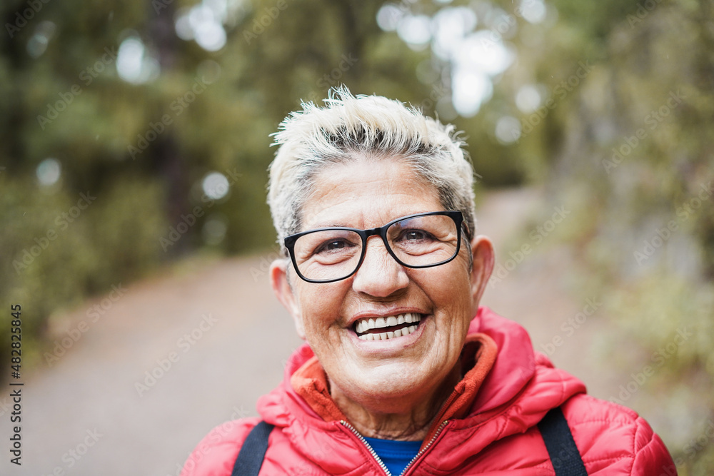 Portrait of senior hispanic woman having fun during trekking day in mountain forest - Focus on face Portrait of senior hispanic woman having fun during trekking day in mountain forest - Focus on face