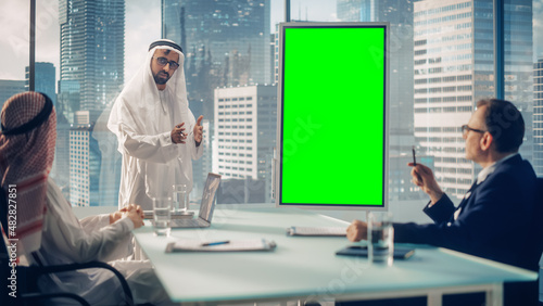 Saudi Businessman Holds Meeting Presentation for International Business Partners. Arab Manager Uses Digital Whiteboard with Vertical Green Screen Mock Up Display. Saudi, Emirati, Arab Office Concept.