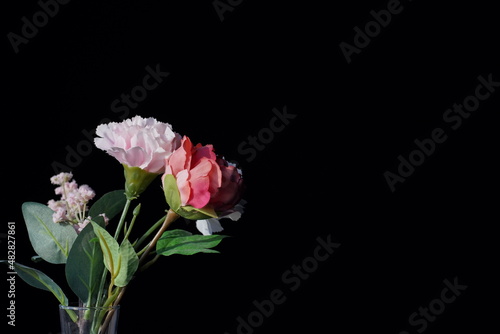 roses artificial pink flowers stand in a vase on a black homogeneous background taken close-up in natural light