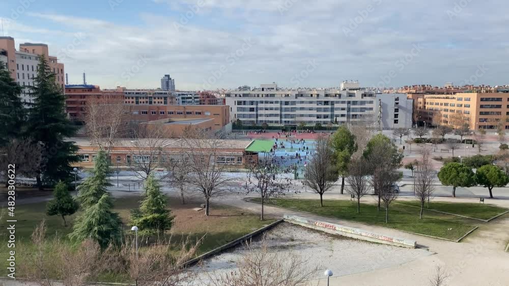 Panoramic view of children playing in a school playground in an urban setting Panoramic view of children playing in a school playground in an urban setting
