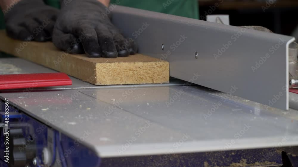 Close up carpenter works on planing machine in workshop. Woodworking and making wooden detail