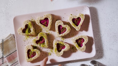 pidgin with cocktail glasses over beetroot heart shaped sandwiches for valentine's day