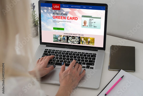 Green card in a search engine on the computer. laptop and american flag