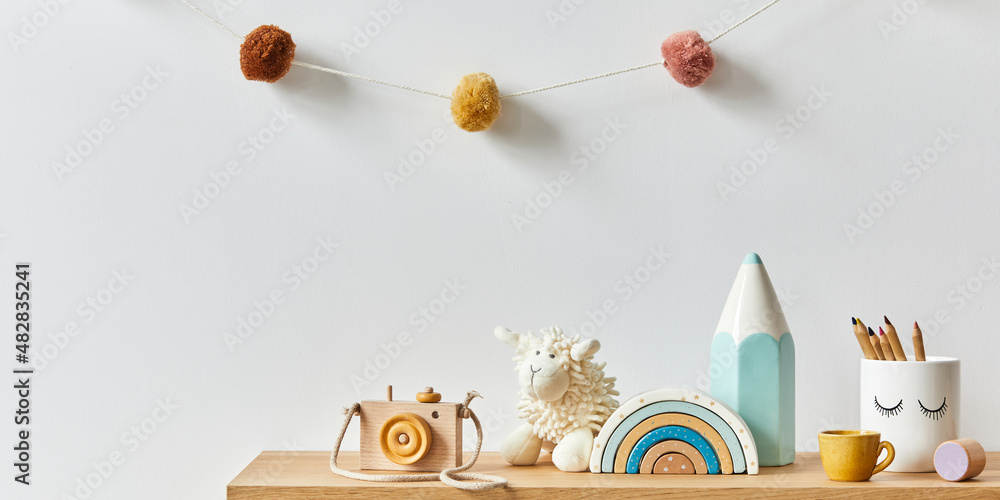 Stylish scandinavian newborn baby room with toys, plush animal, photo camera, dolls and child accessories. Cozy decoration and hanging cotton balls on the white wall. Copy space. - obrazy, fototapety, plakaty 