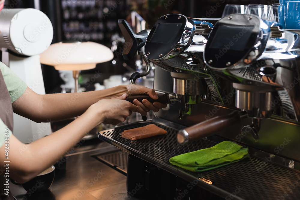 Cropped view of barista working with coffee machine near rags in cafe.