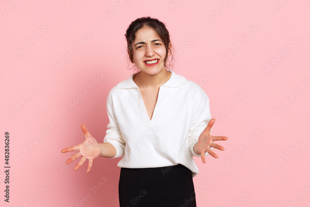 Angry young arabian girl in white blouse posing isolated on pink background. Concept of emotions, problems, inner world Angry young arabian girl in white blouse posing isolated on pink background. Concept of emotions, problems, inner world