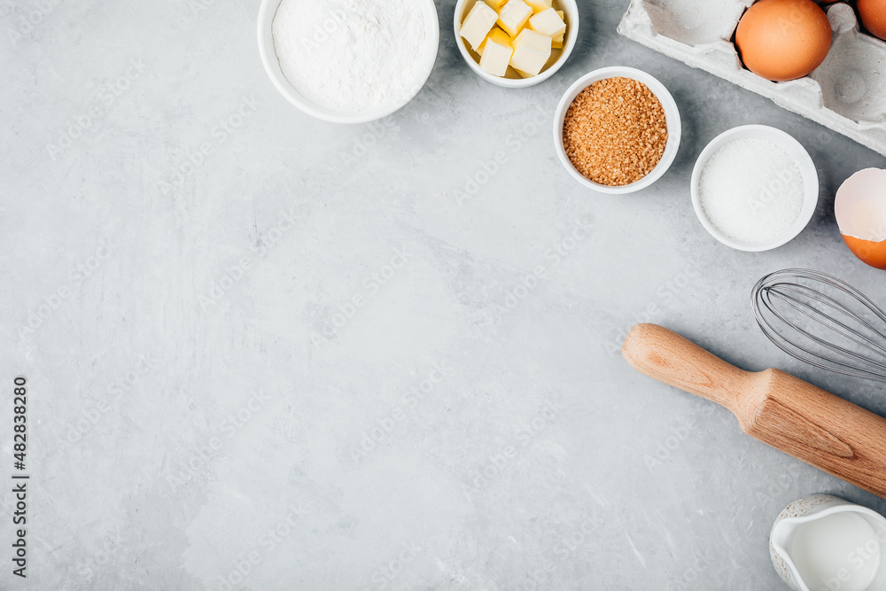 Baking ingredients. Flour, eggs, sugar, butter, roller pin and whisk on the kitchen table. Baking ingredients. Flour, eggs, sugar, butter, roller pin and whisk on the kitchen table.