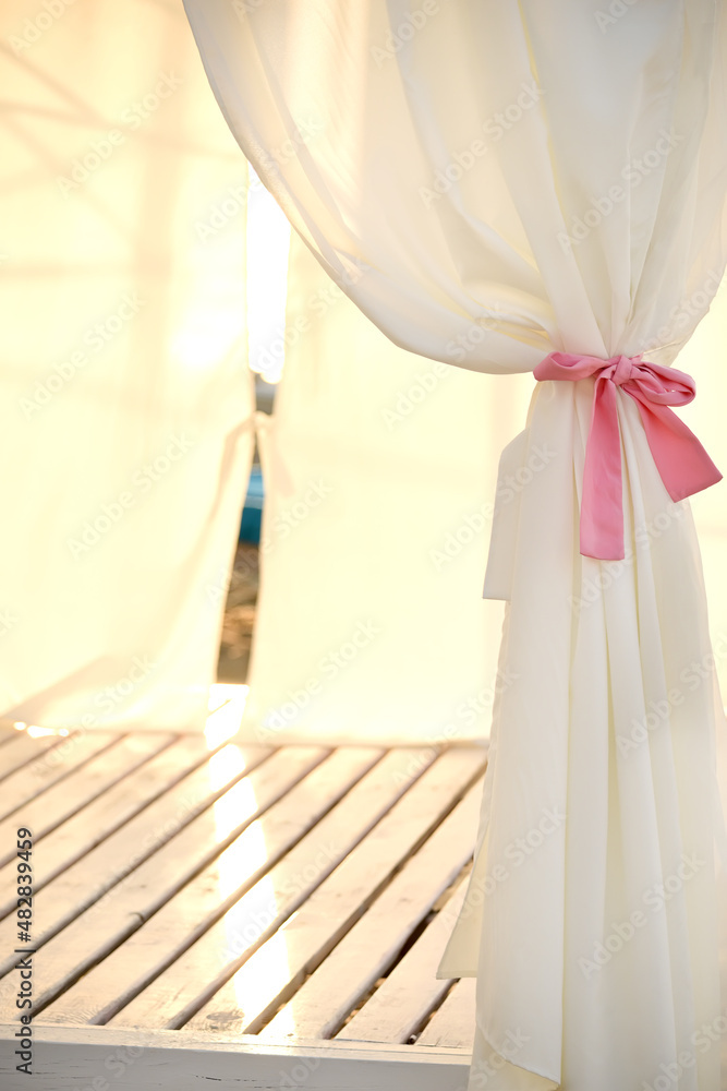 A pergola with a light fabric in the gentle light of an early morning by the sea. A pergola with a light fabric in the gentle light of an early morning by the sea.