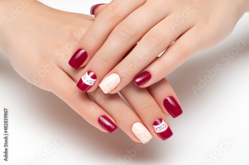 Burgundy, beige manicure with white monograms on short square nails close-up on a white background. Gel manicure.