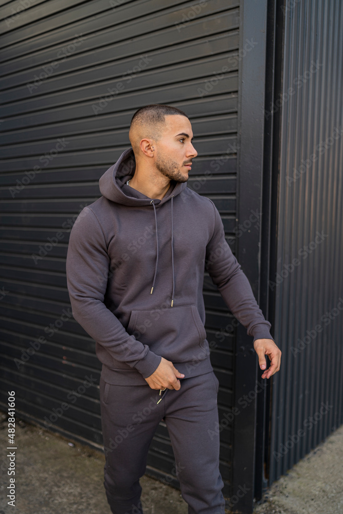 Chico joven tatuado atractivo con ropa urbana posando en la calle