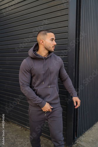 Obraz na płótnie Chico joven tatuado atractivo con ropa urbana posando en la calle w salonie