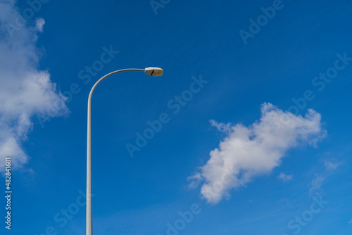 Escena de cielo azul despejado con algunas nubes y farola
