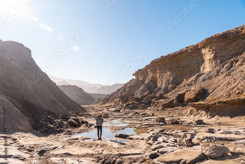 A young woman walking along the water in the desert on a trek in the Travertino waterfall and Rambla de Otero in the desert of Tabernas, Almería province, Andalusia photo