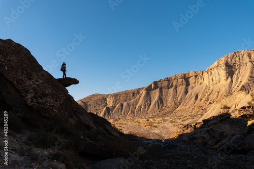 Silhouette of a young woman climbing on a stone in the Tabernas desert, Almería province, Andalusia. A trek in the Rambla Las Salinas