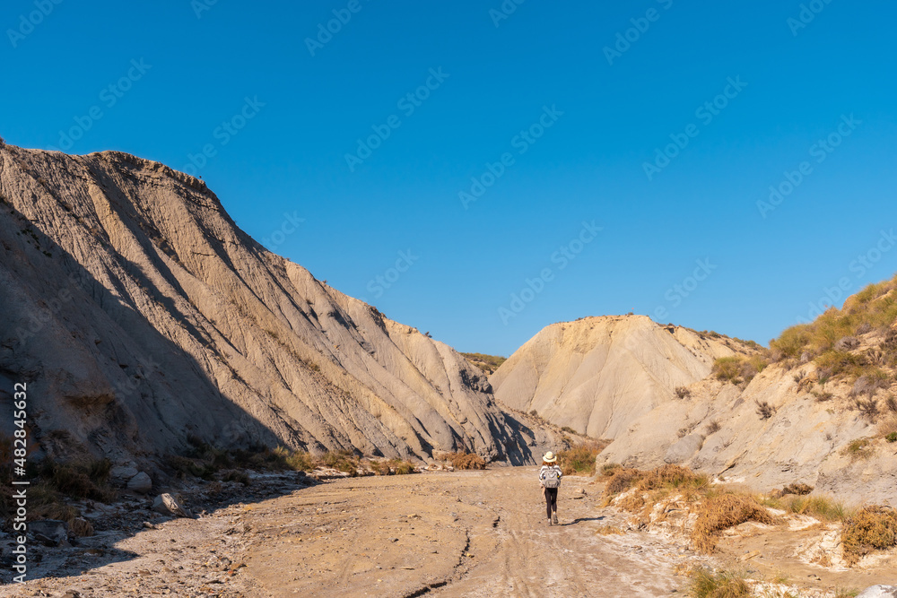 A young hiker with backpack and hat in the desert of Tabernas, Almería province, Andalusia. On a trek in the Rambla del Infierno