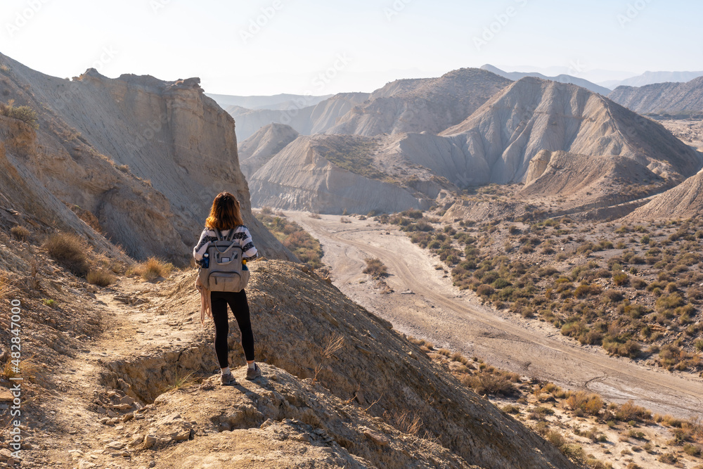A young hiker girl up in the canyon on Rambla de Lanujar in the Tabernas desert, Almería province, Andalusia. Trekking in the desert, lifestyle